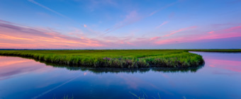 14mm HDR photograph of a pastel sunset over fresh summer green grasses of Cedar Run Dock Road salt marsh.