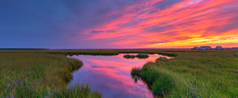 A smoldering sunset burns over the lush summer green salt marsh at Cedar Run Dock Road photographed at 14mm focal length. Seven bracketed exposures one f-stop apart merged for HDR to maximize dynamic range.