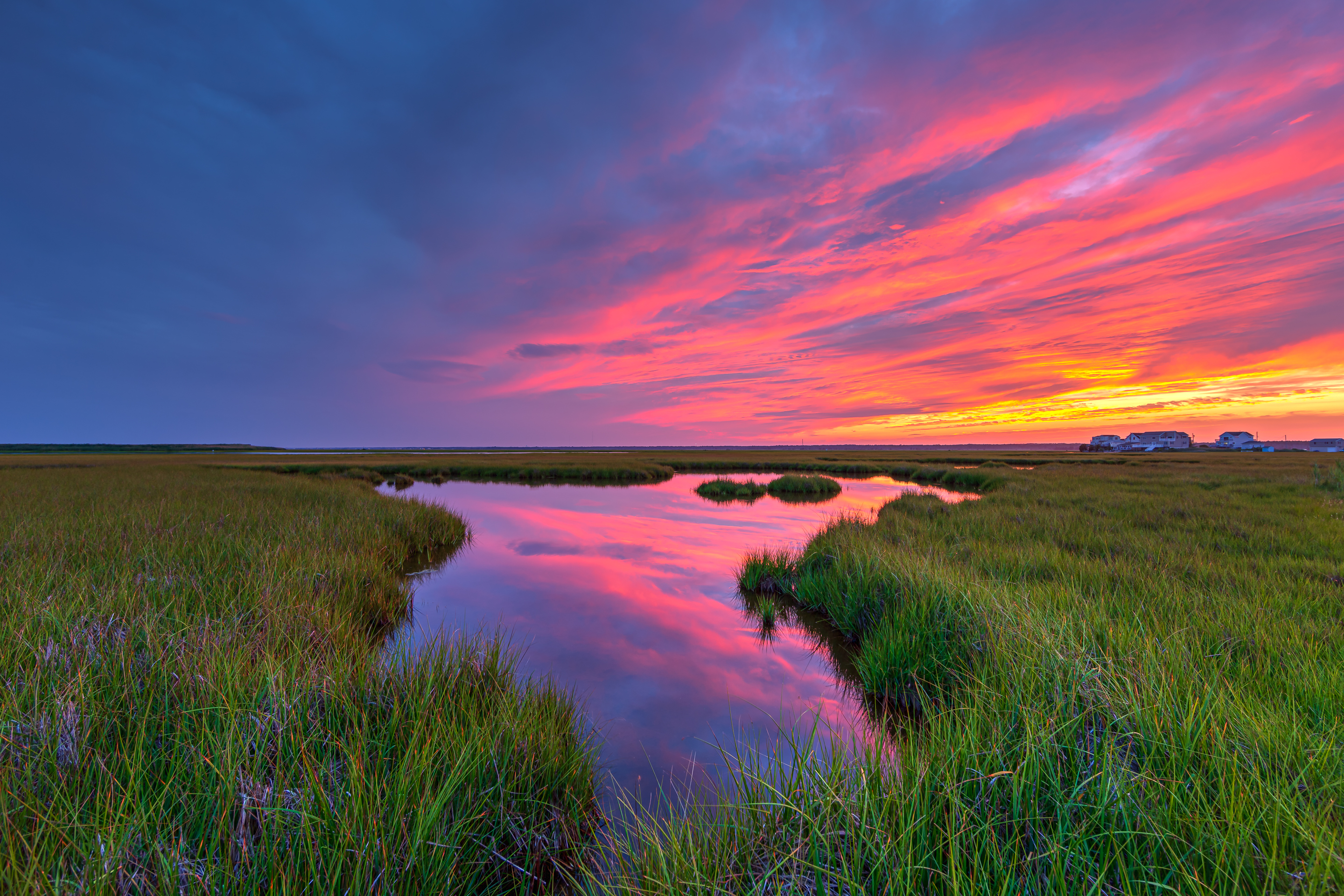 A smoldering sunset burns over the lush summer green salt marsh at Cedar Run Dock Road photographed at 14mm focal length. Seven bracketed exposures one f-stop apart merged for HDR to maximize dynamic range.