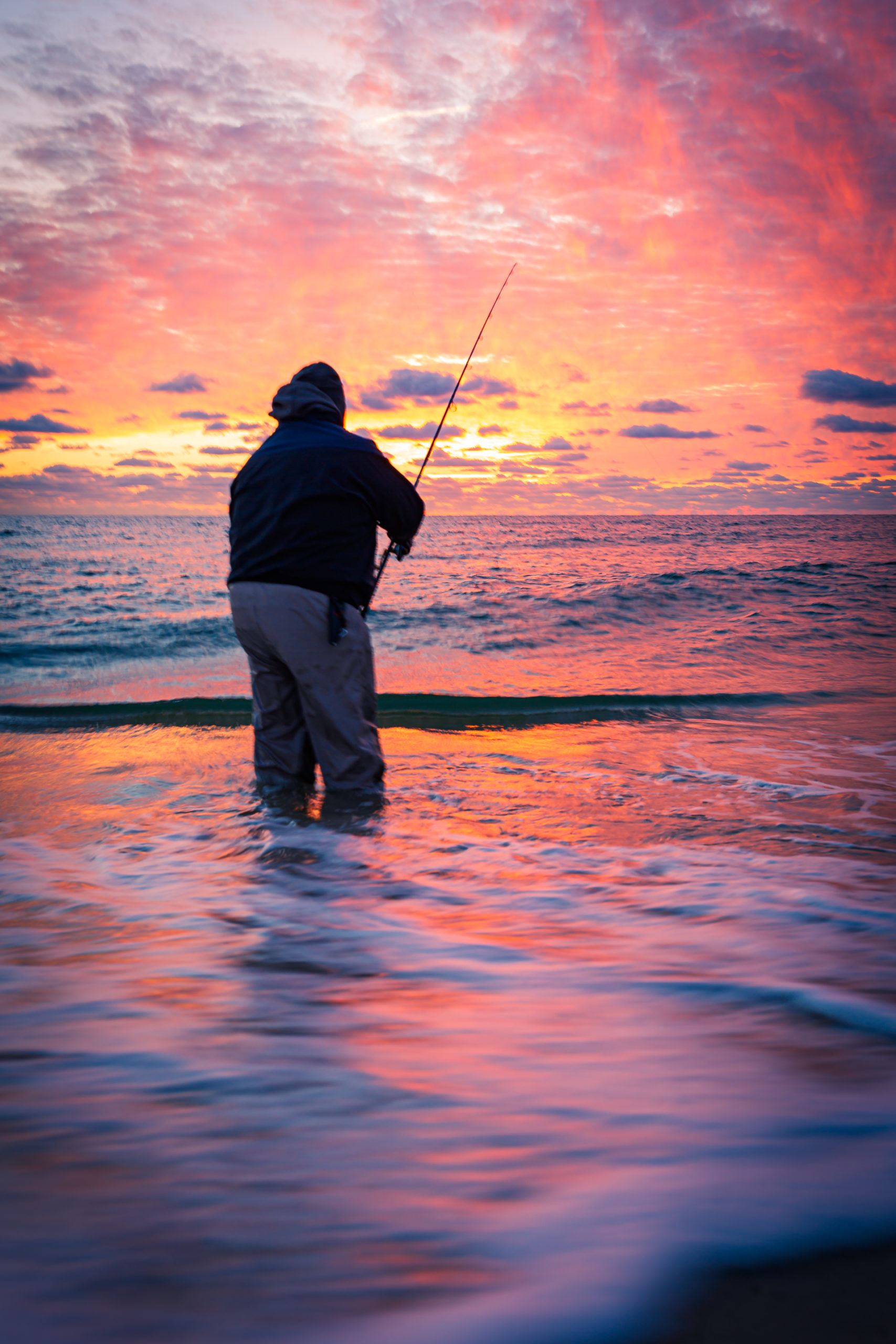 35mm sunrise photograph of Dan Molyneux plugging the top water as he surf fishes for striped bass during the 2023 fall run. Captured on Long Beach Island on 12 November 2023, Ship Bottom, New Jersey.