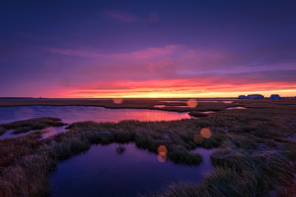 14mm wide angle sunset photo of an intense purple and red sky blazes the horizon with the September 2026 nor-easter approaching. Rain drops speckle the lens.
