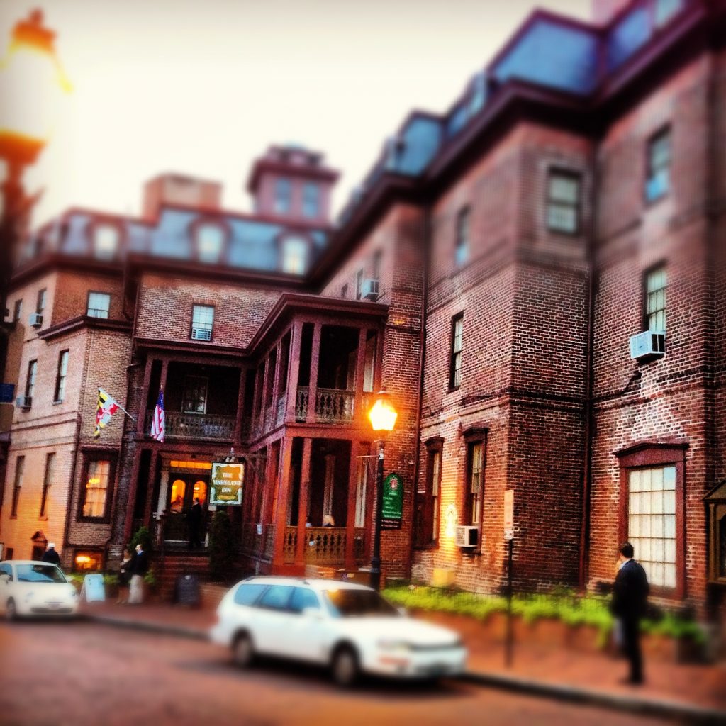 Annapolis street scene with brick buildings, cars and people under glowing streetlights.