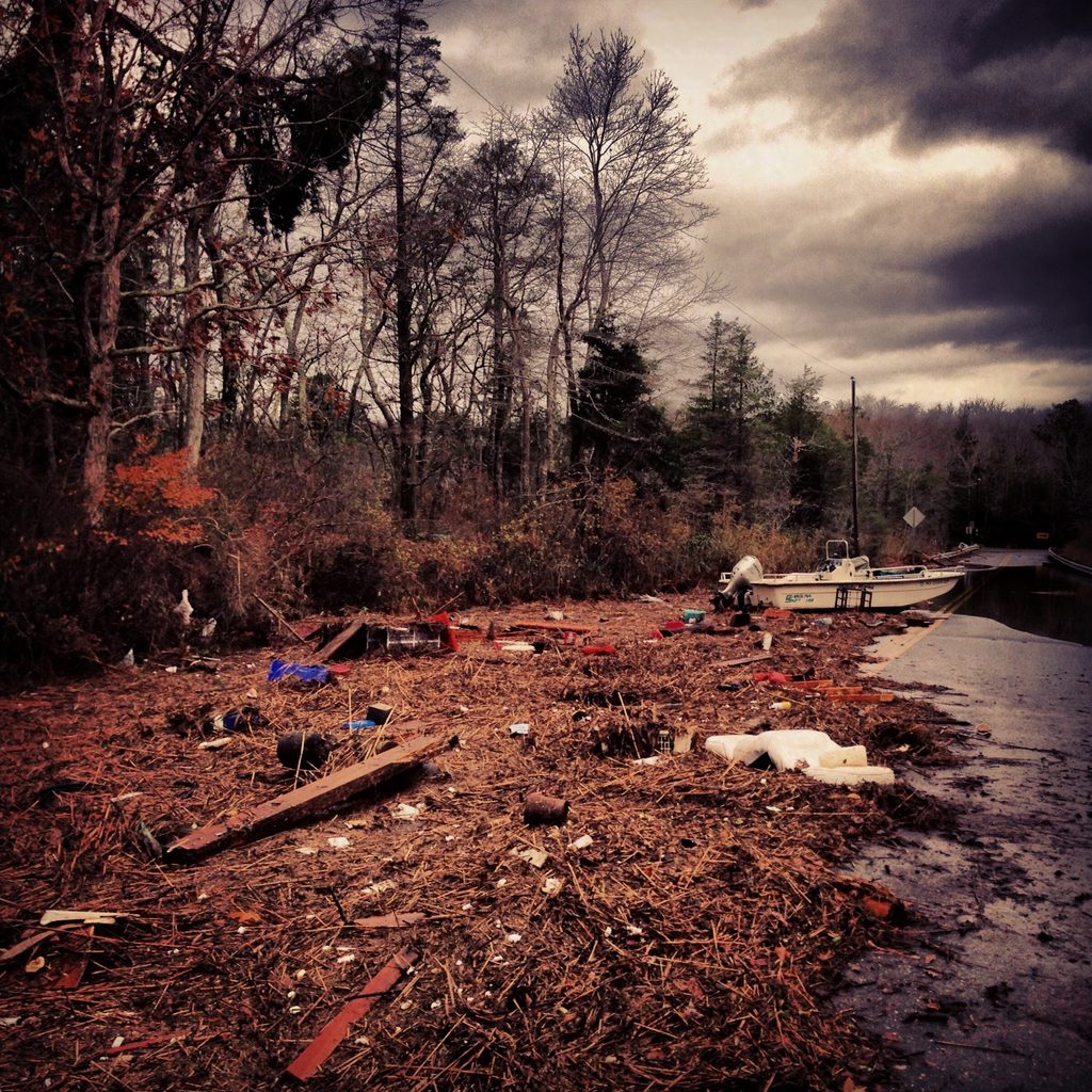 Storm debris, marsh grasses and scattered material stretch across Cedar Run Dock Road.