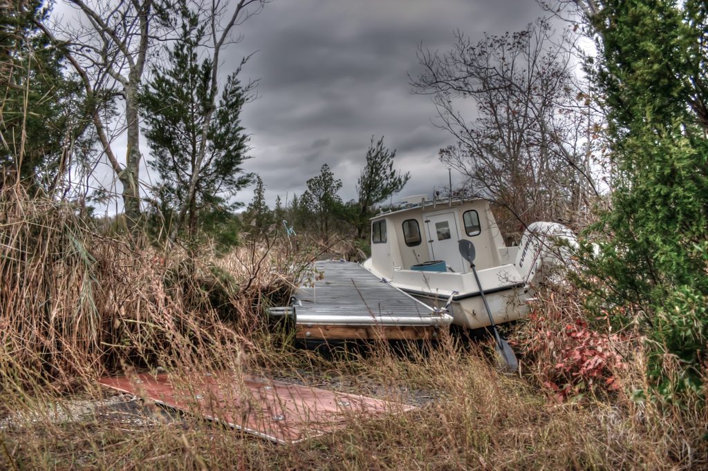 A small boat and the floating dock to which it is tied rest on dry ground.